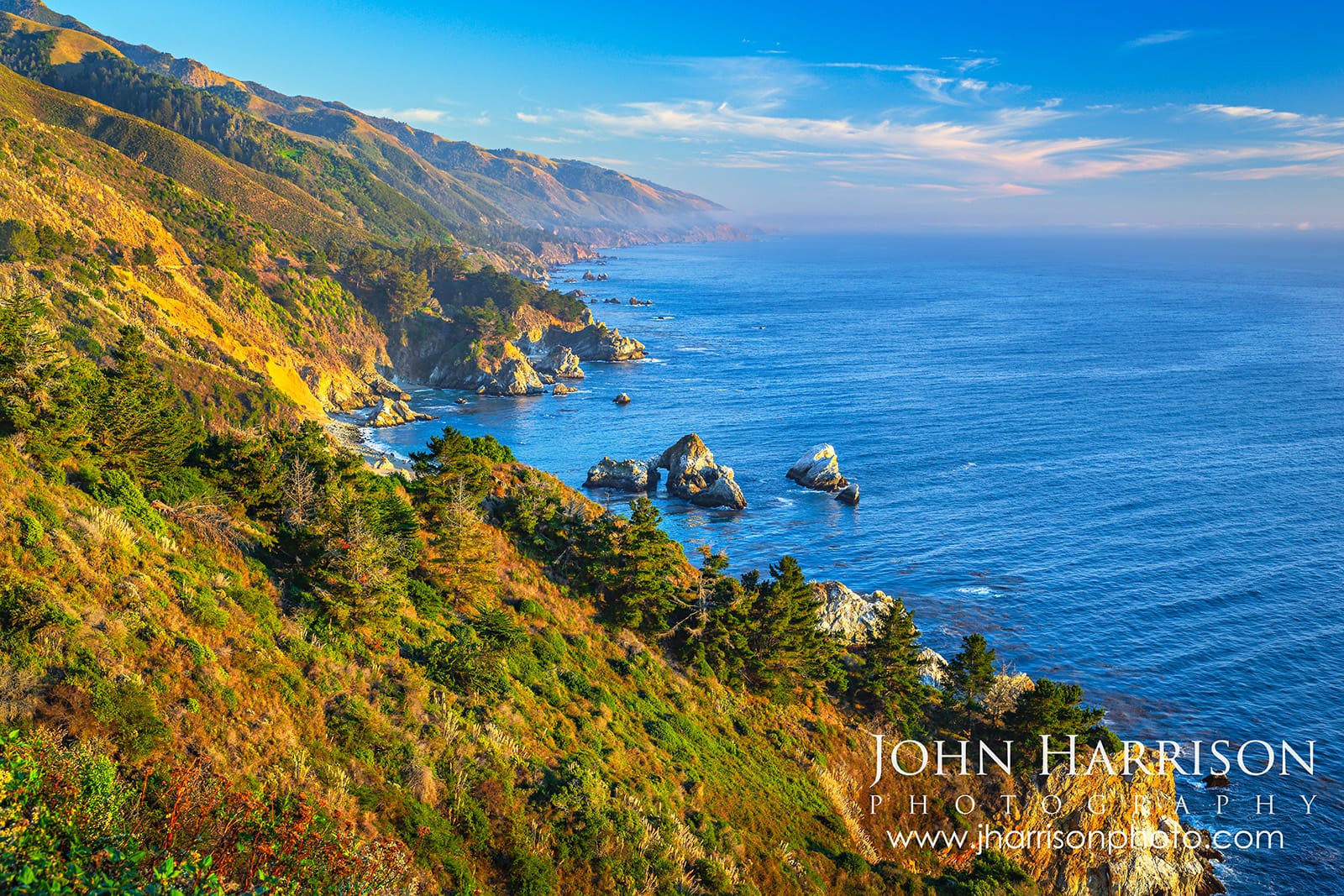 Golden hour view of the Big Sur coastline near Garrapata State Park, featuring rugged cliffs, Pacific Ocean sea stacks, and a hidden natural rock arch along California's Highway 1.