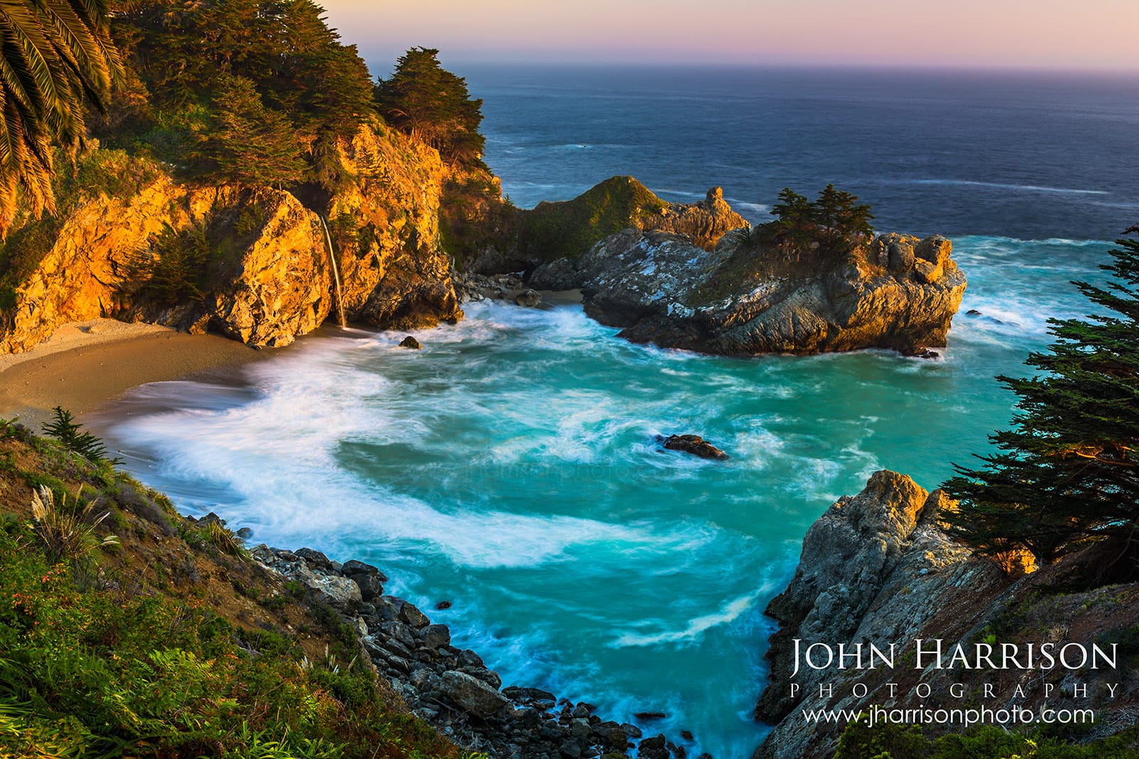Fine art photograph of McWay Falls at sunset in Big Sur, California, featuring a lone palm tree and lush green foliage framing a turquoise cove where a waterfall spills onto the beach.