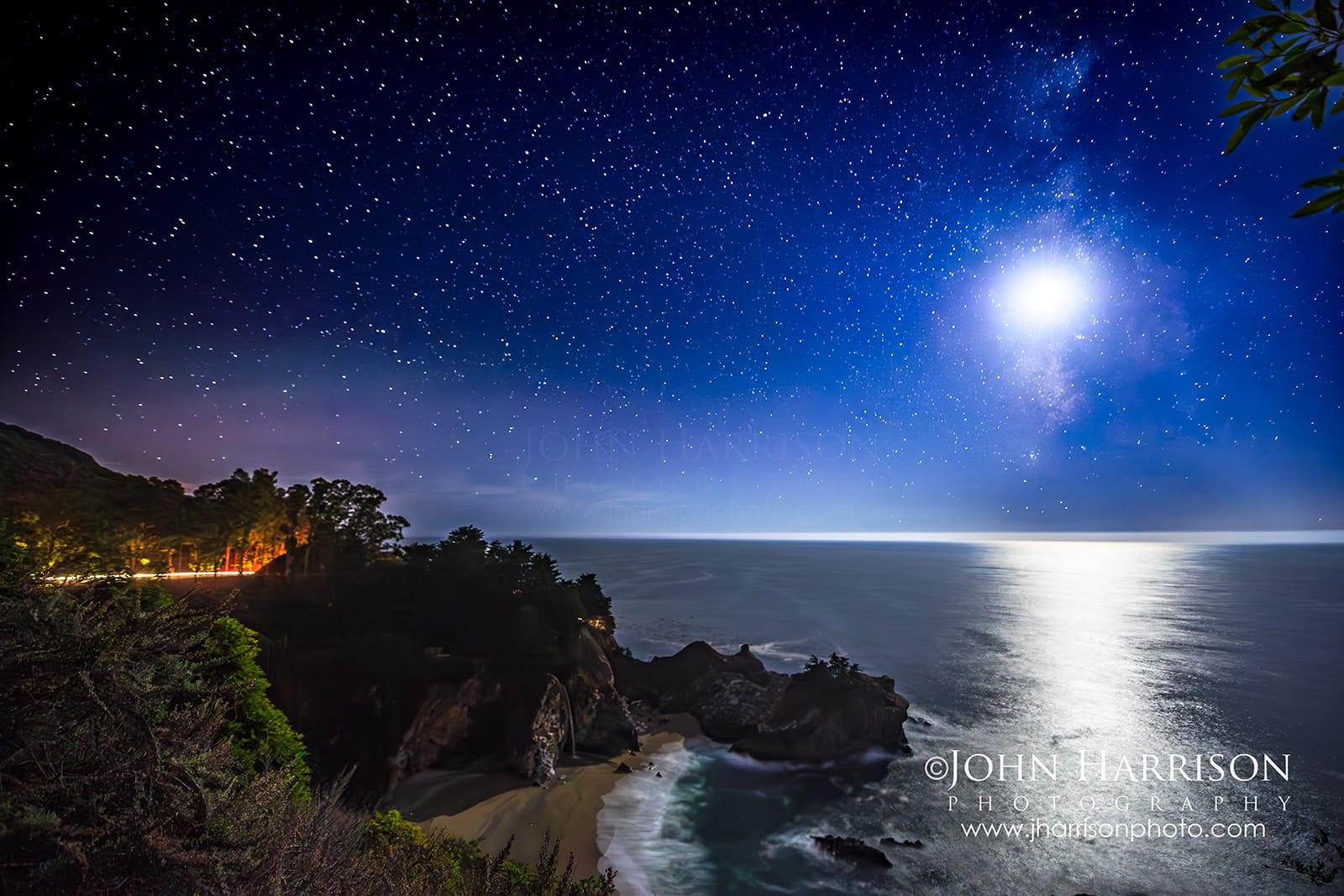 Moonrise and Milky Way above McWay Falls in Big Sur California with long exposure ocean reflections and Highway 1 light trails at night.