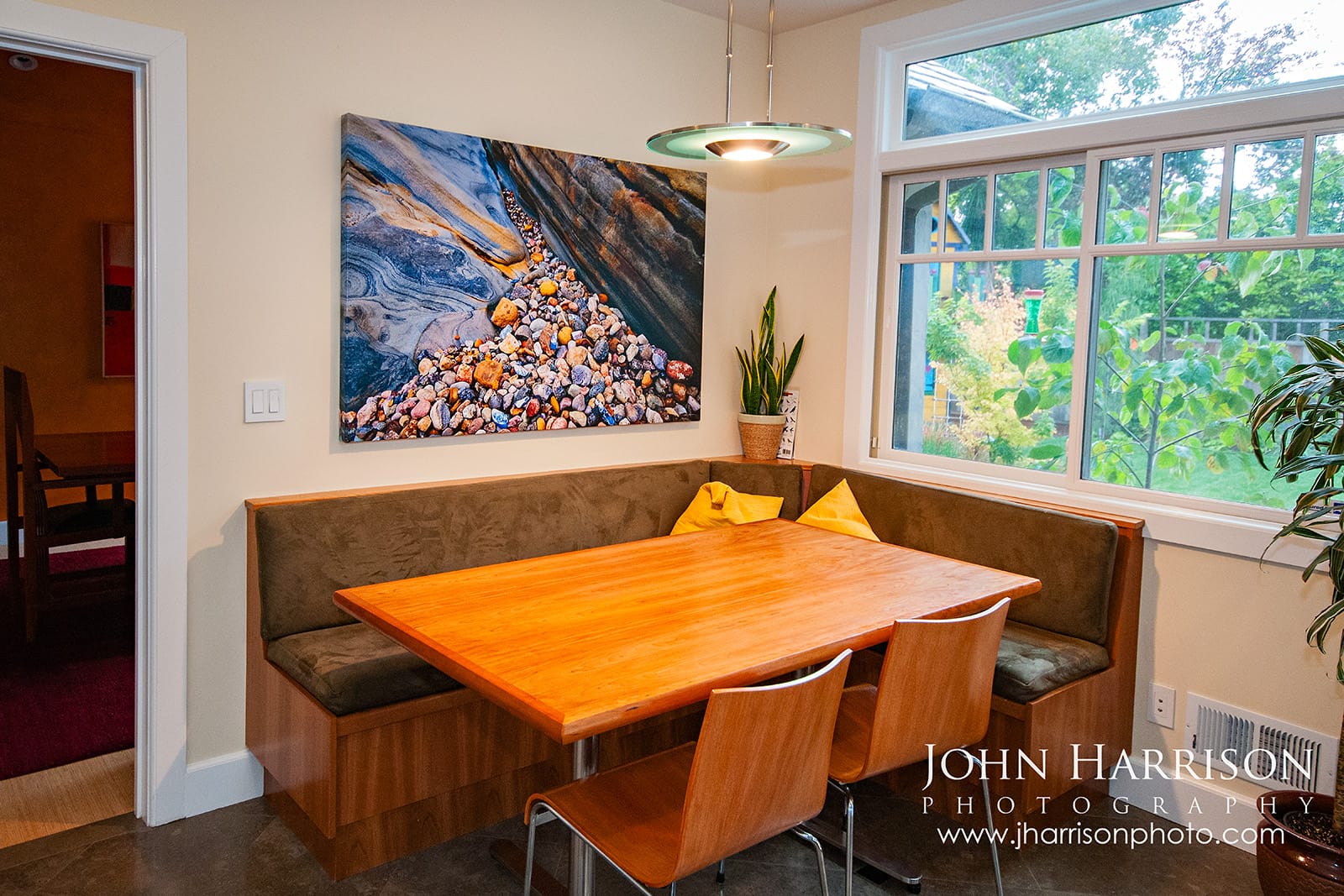 "Entrance to the Stones in Concert", a 40 × 60-inch canvas Giclée fine art photograph of colorful rock textures and pebbles at Weston Beach in Point Lobos, installed above a dining nook in a collector’s home.