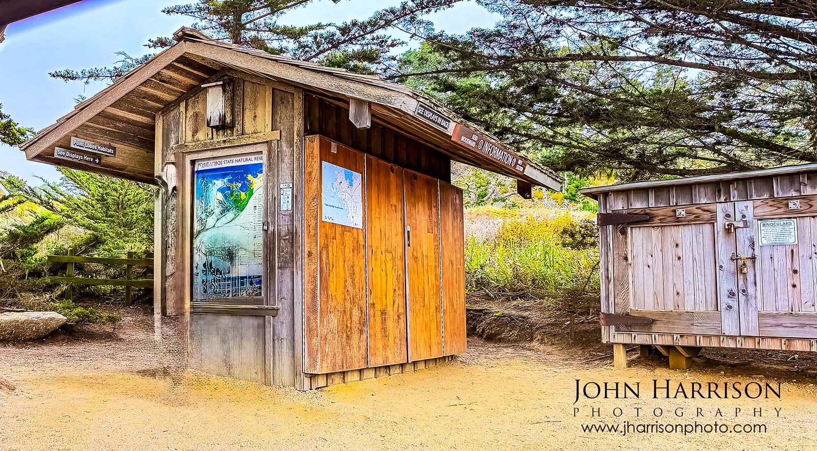 Rustic docent information station at Point Lobos State Natural Reserve with visitor maps and wildlife binoculars.