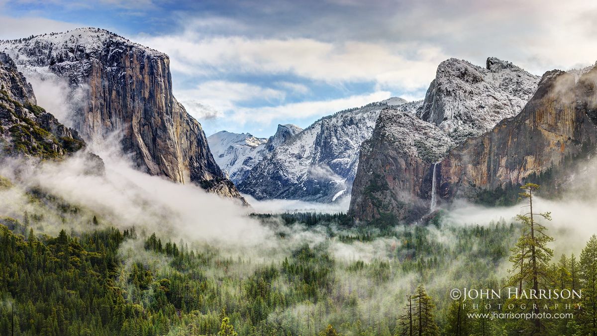 Winter panorama from Tunnel View in Yosemite National Park showing El Capitan, Bridalveil Fall, snow-covered granite cliffs, and mist drifting through Yosemite Valley after a storm.