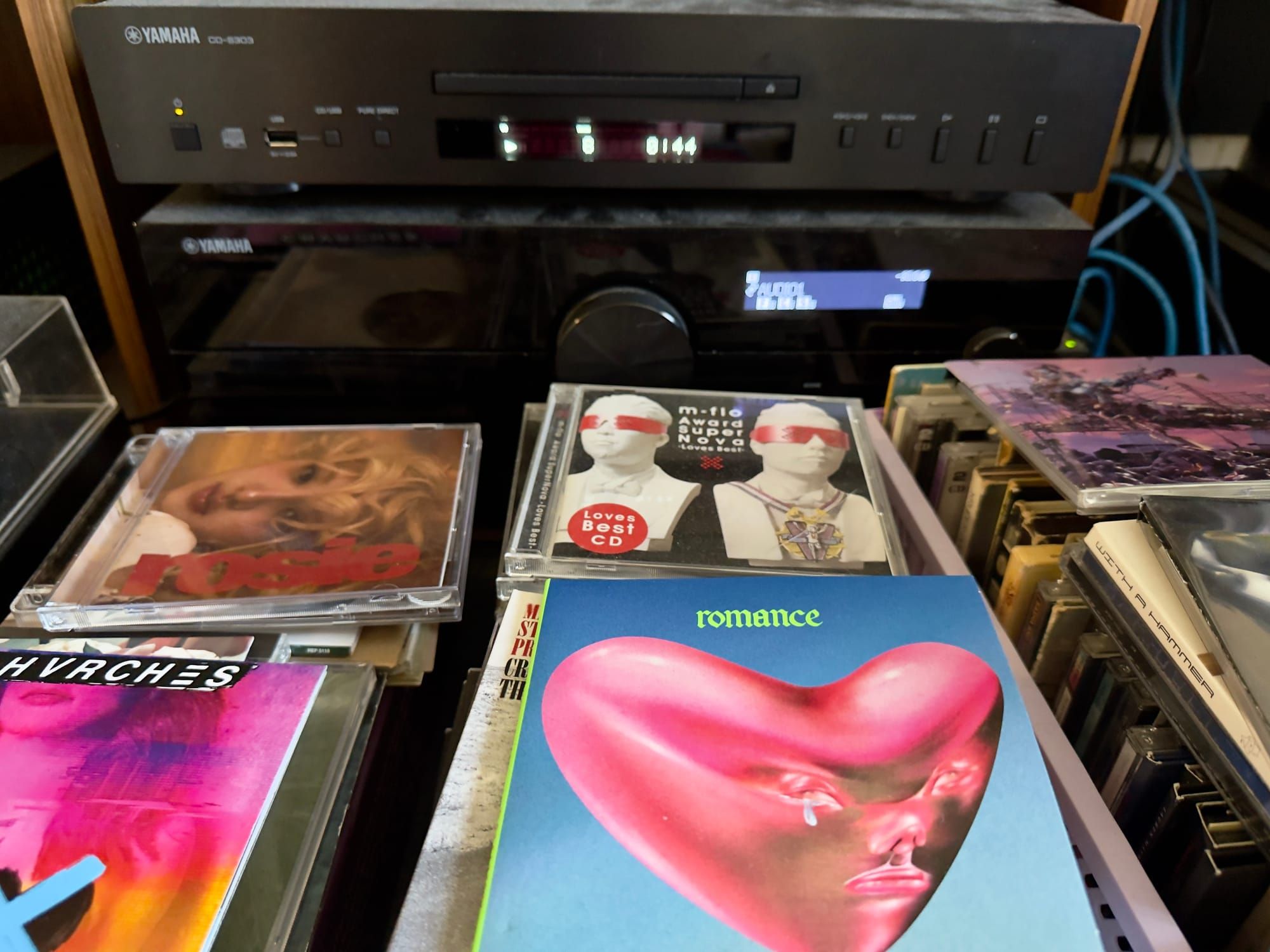 A pile of CDs sitting in front of a CD player.