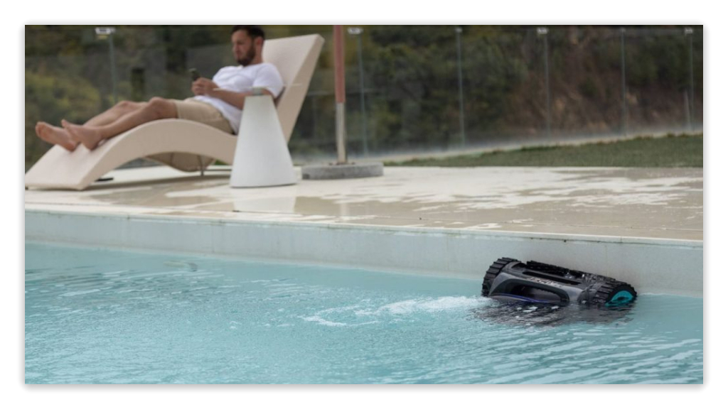 Aiper pool cleaning robot operating in a swimming pool with a person relaxing nearby.