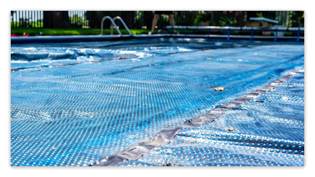Close-up of a dirty pool cover, with debris and water spots