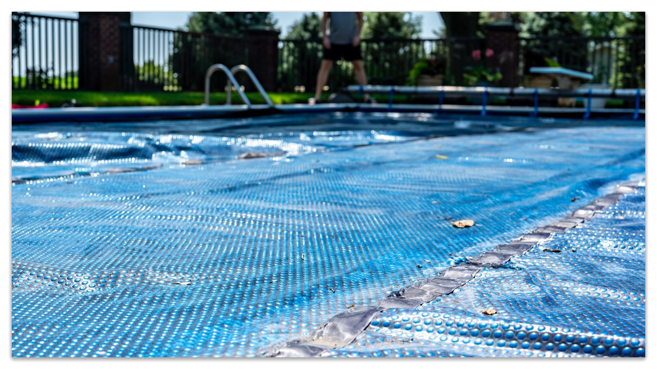 A man would clean leaves and dust on the pool cover.