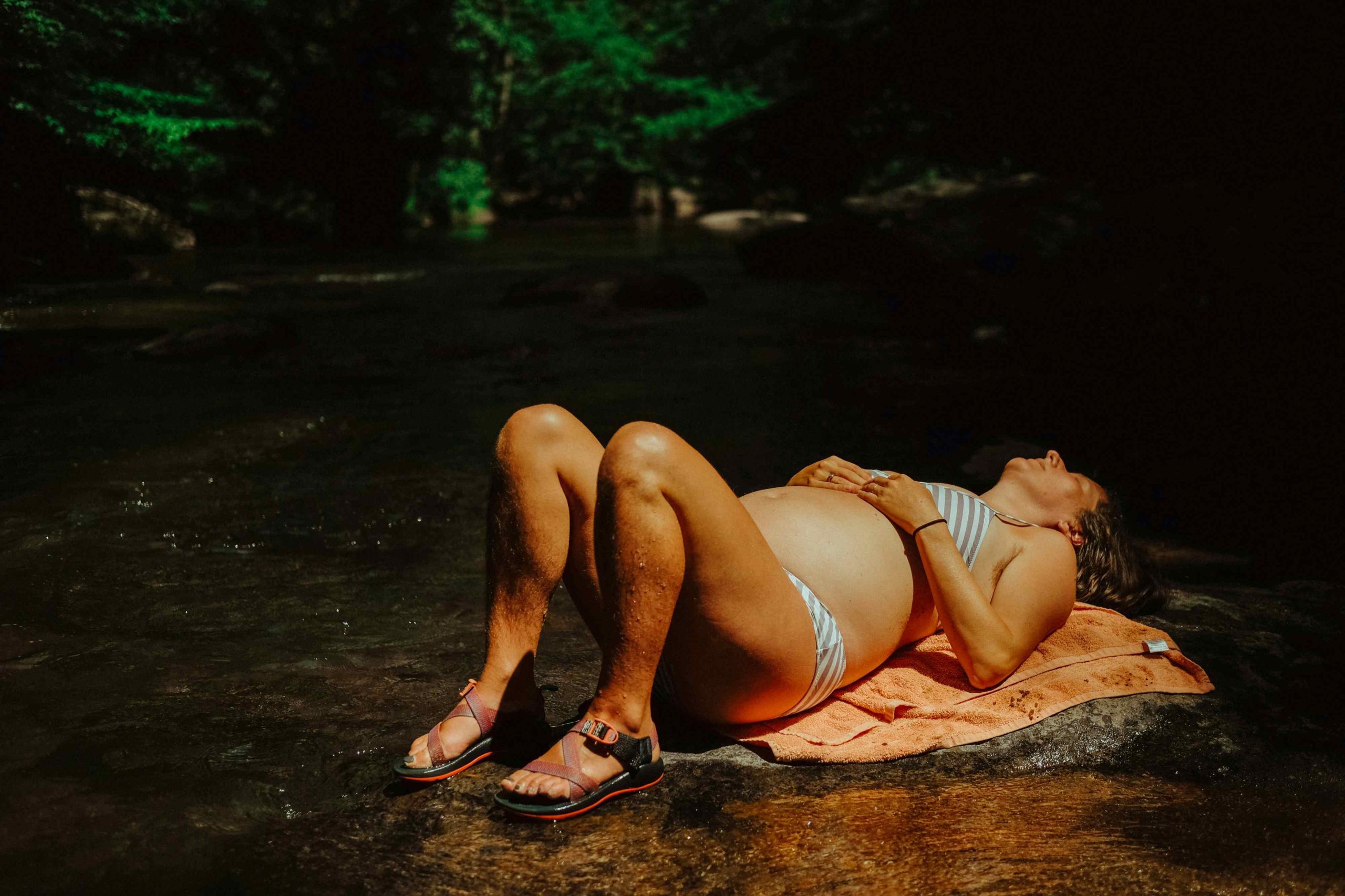 Pregnant woman lying by the water.