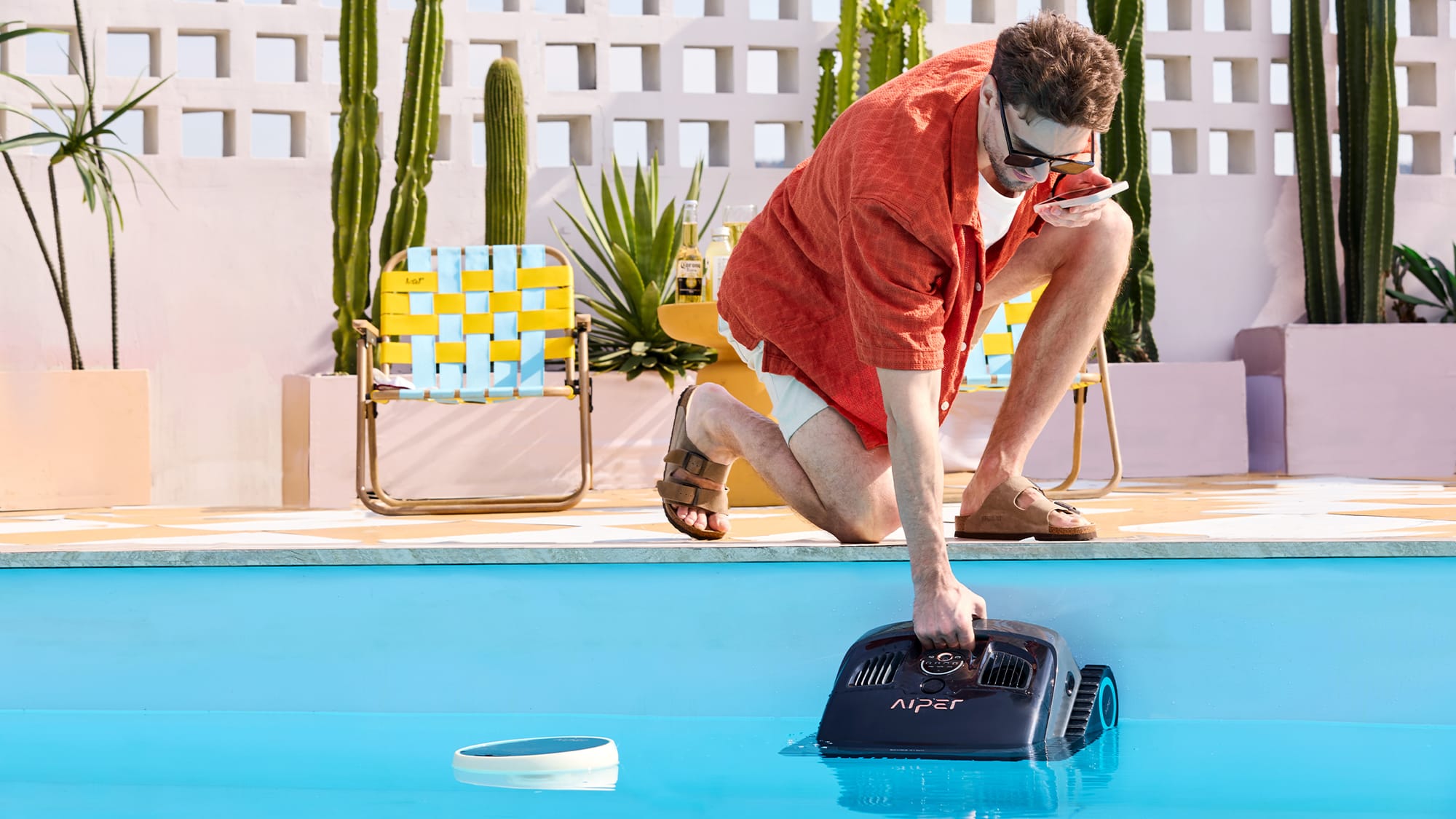 Man retrieves pool robot from poolside