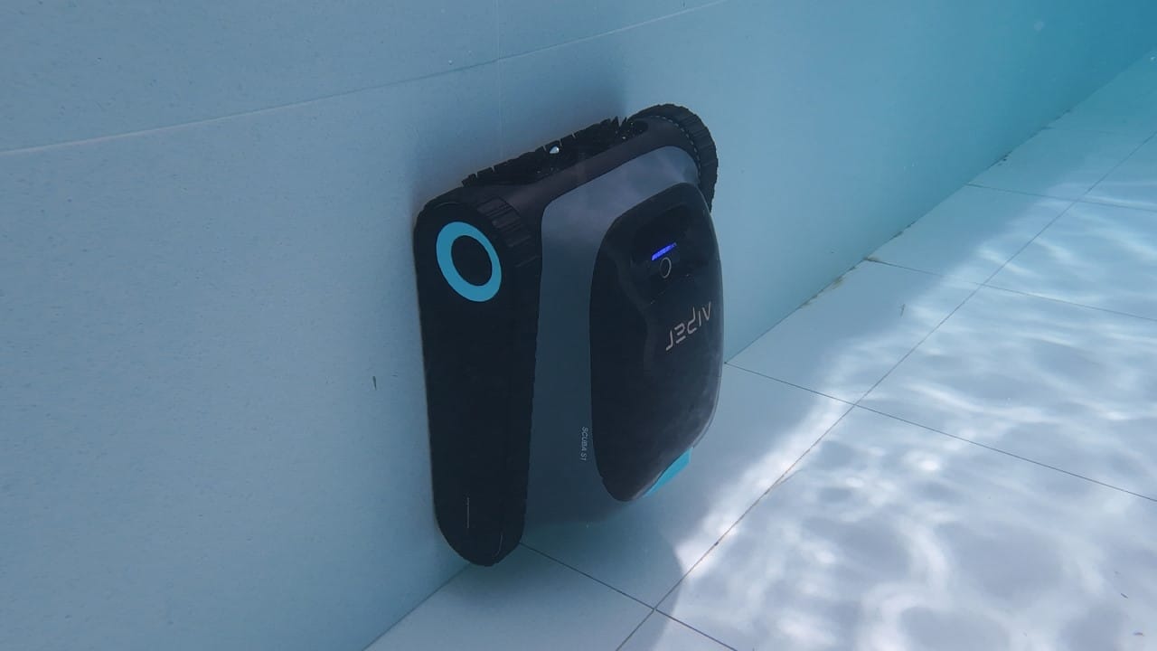 Robotic pool cleaner scrubbing the walls of an in-ground pool.