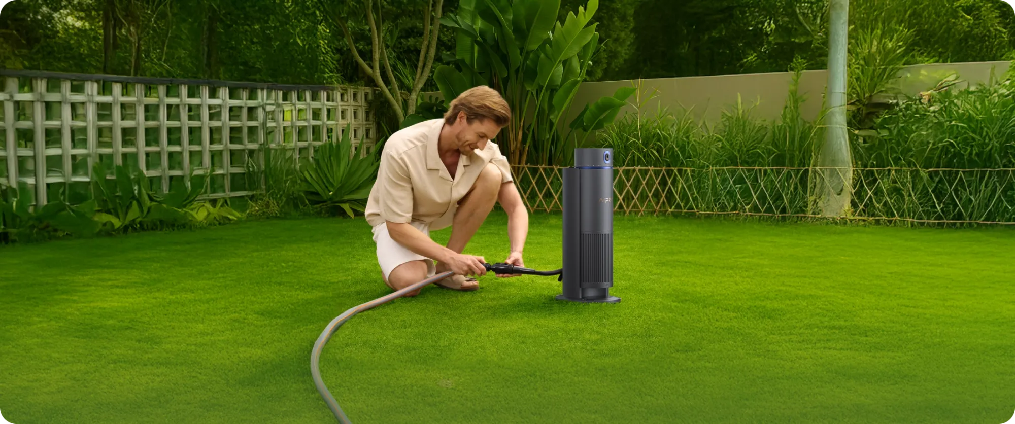 A user connecting a water pipe to an irrigation tool before watering the lawn.