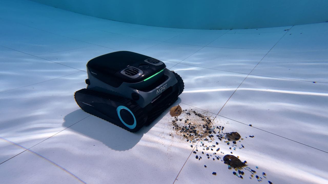 A robotic pool cleaner vacuuming dead algae dust and debris from the pool floor after chemical treatment.