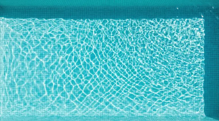 Sunlight penetrating clear pool water indicating proper sanitation and constant flow for health safety.