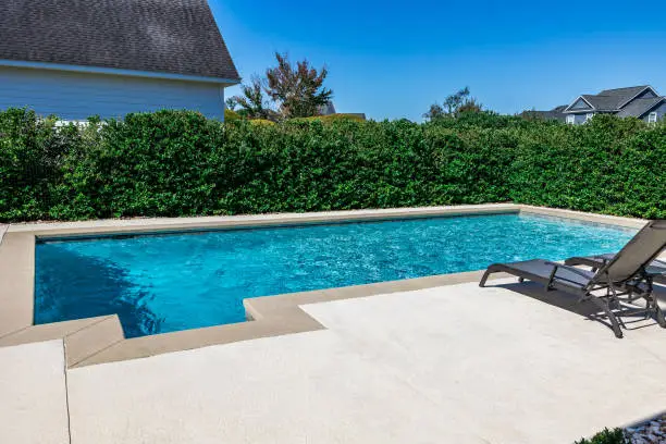 Clear blue concrete swimming pool with a smooth, long-lasting painted finish in a residential backyard.