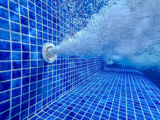 Pool return jet releasing aerated water, showing circulation that helps cool pool water when run at night.