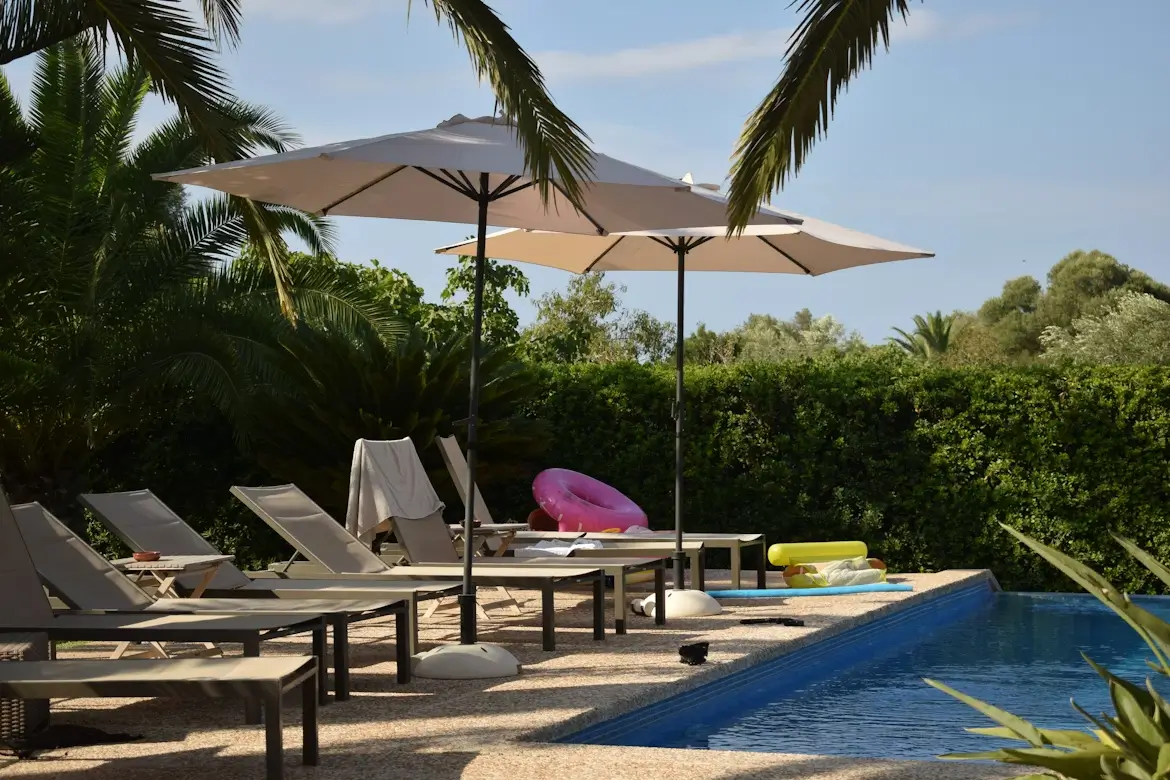 Shade sail and umbrella covering swimming pool to block direct sunlight.
