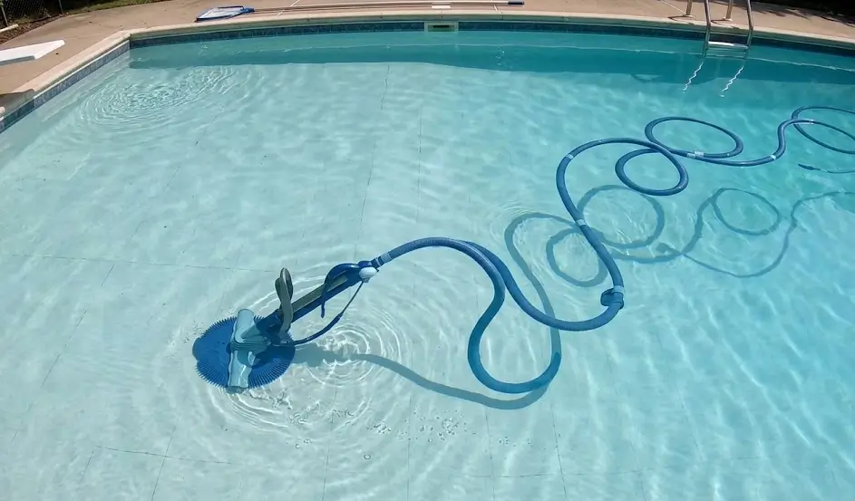 Traditional suction pool cleaner with coiled hoses in swimming pool.