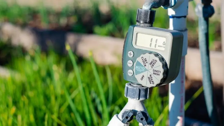 Tap-mounted digital dial traditional sprinkler timer set for fixed schedule irrigation on Australian backyard garden.