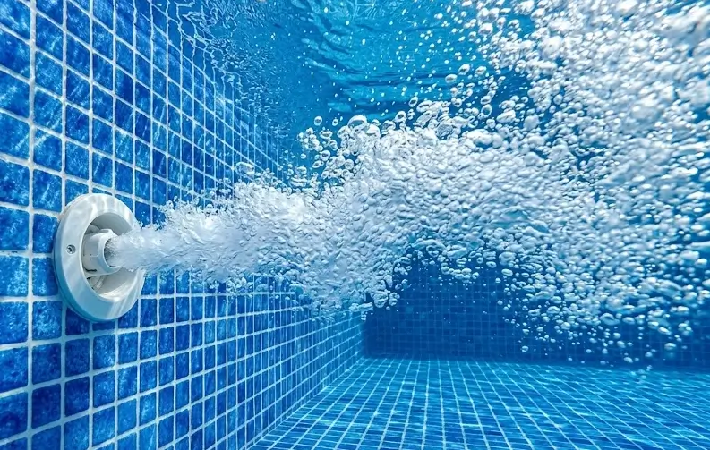Underwater pool return jet releasing steady water to build continuous whirlpool circulation across entire swimming pool.