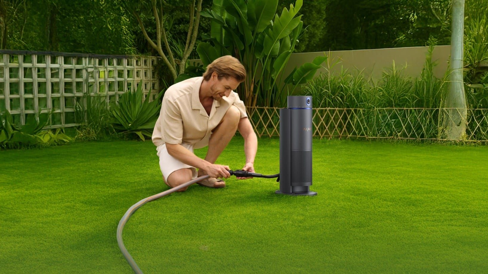 Homeowner connecting a hose to a smart irrigation controller device on a green lawn to automate watering.