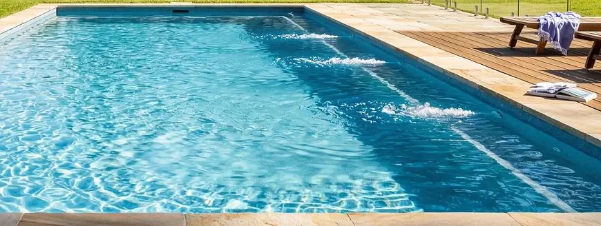 A sunny backyard pool with clear blue water demonstrating effective circulation currents.