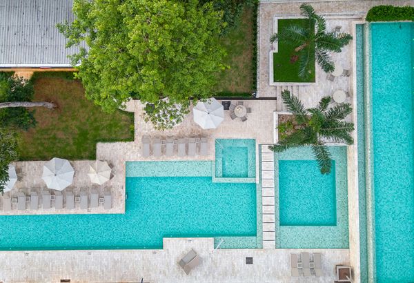An overlooking view of the hotel's backyard with multiple swimming pools, each of which is very clean.