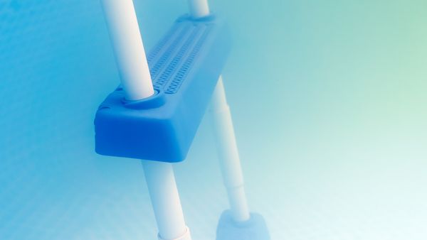 A close-up shot of a blue and white pool ladder partially submerged in cloudy water.