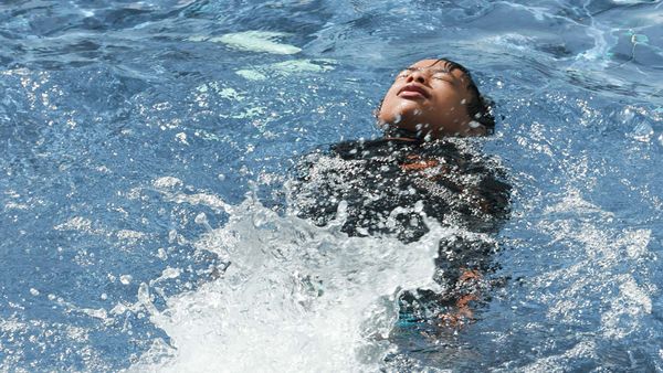 A swimmer experiencing the initial cold shock response, with water splashing around their head and shoulders.