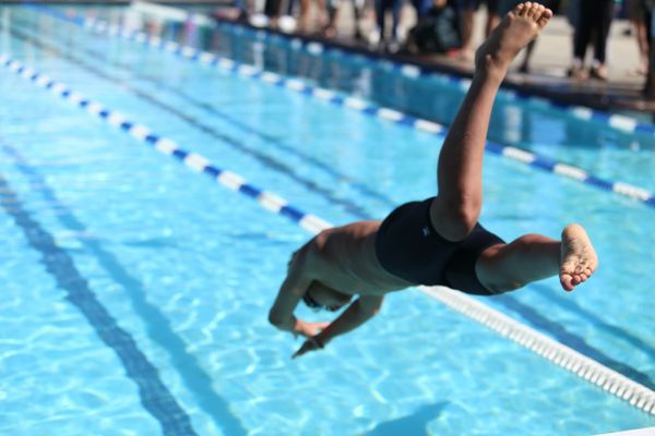 A male swimmer diving into a pool, representing the full-body workout and muscle-building benefits of swimming.