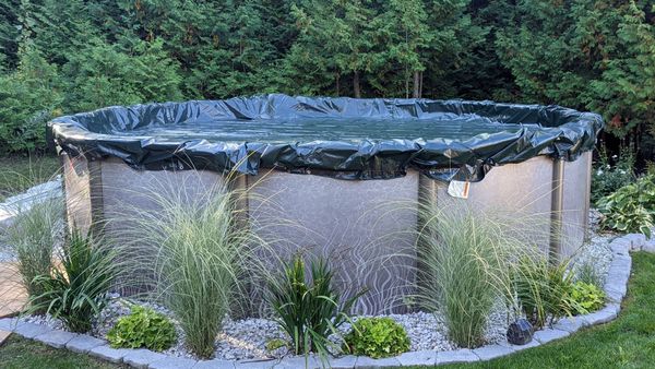 An above-ground swimming pool properly covered with a winter cover, ready for the cold season.