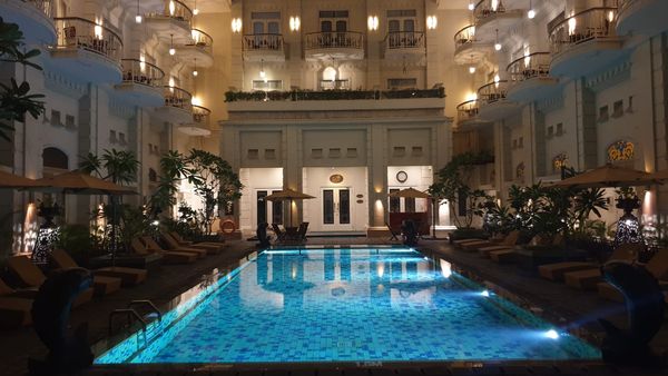 A beautifully illuminated outdoor swimming pool at night, its bright blue water glowing with light