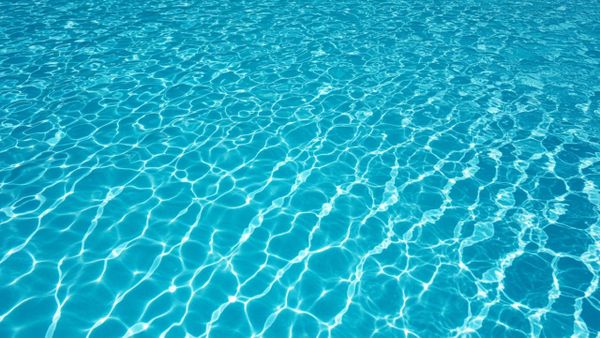 a stunningly clear swimming pool, with sunlight creating a sparkling "polished" effect on the water's surface.
