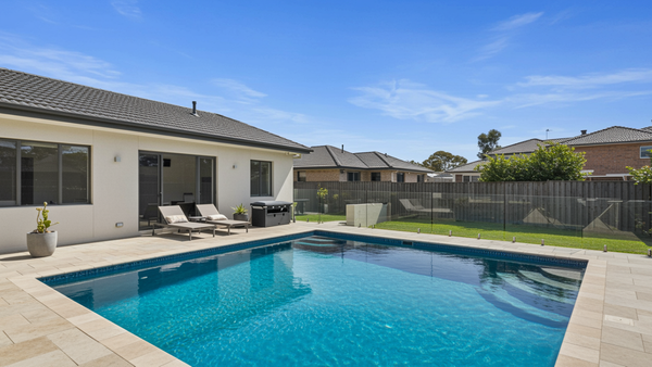 A pristine backyard swimming pool in Australia with sparkling blue water, illustrating the results of learning how to look after a pool.