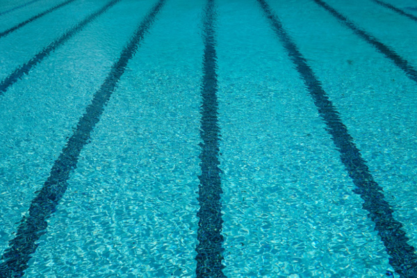 Agua azul clara de piscina con líneas de carril