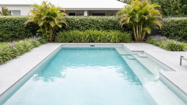 The clean pool surrounded by the low-maintenance greenery.