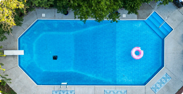 Aerial view of a residential swimming pool with a pool cleaner left in the water.