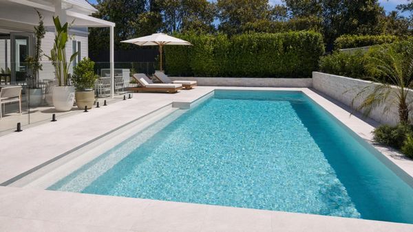 An immaculate, newly resurfaced backyard swimming pool in Australia with crystal-clear water under the summer sun.