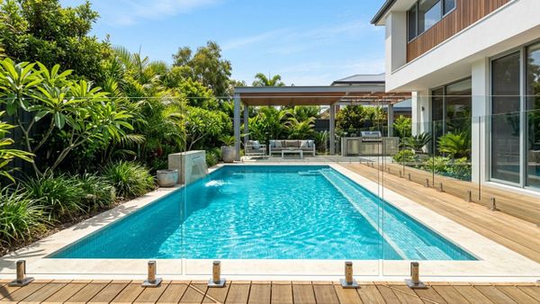 A pristine and crystal-clear frameless glass pool fence in a sunny modern backyard.