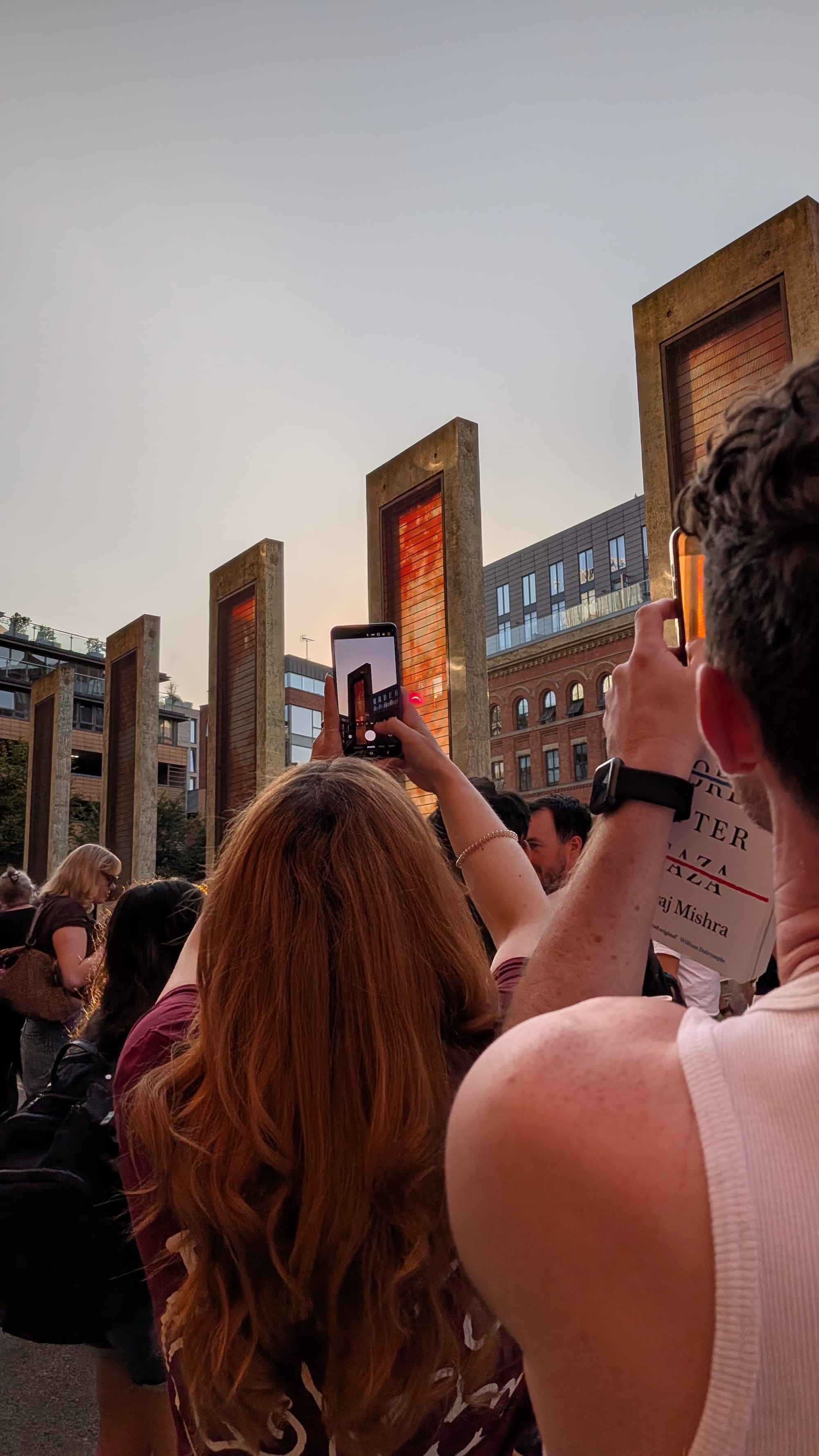 People photographing the Sun through the sculptures. The Sun is visibly eclipses and red.