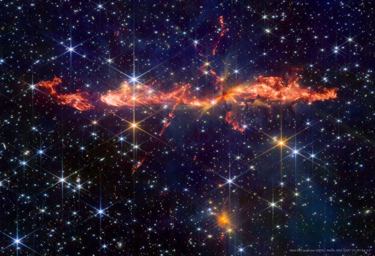 the background of the image is filled with stars. In the center a large, mostly stright jet that looks like flames is visible. smaller jets criss cross this one. 