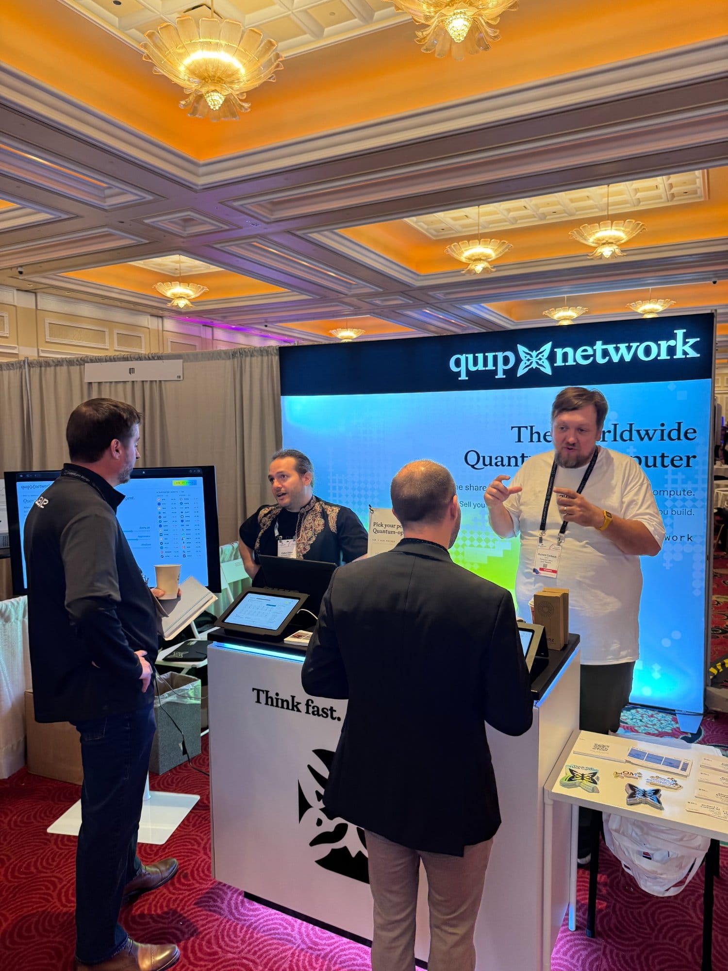 Quip Network co-founders Colton Dillion and Richard Carback talking with two attendees at the booth.