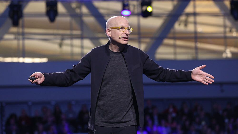 Author and marketing expert Seth Godin on a stage, speaking to an audience.