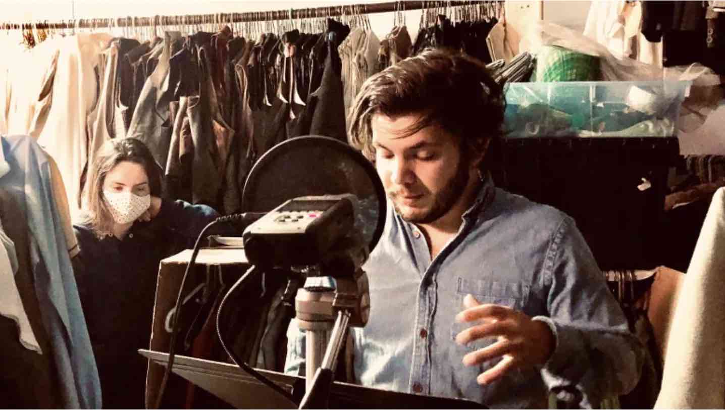 A man recording a podcast in his wardrobe.