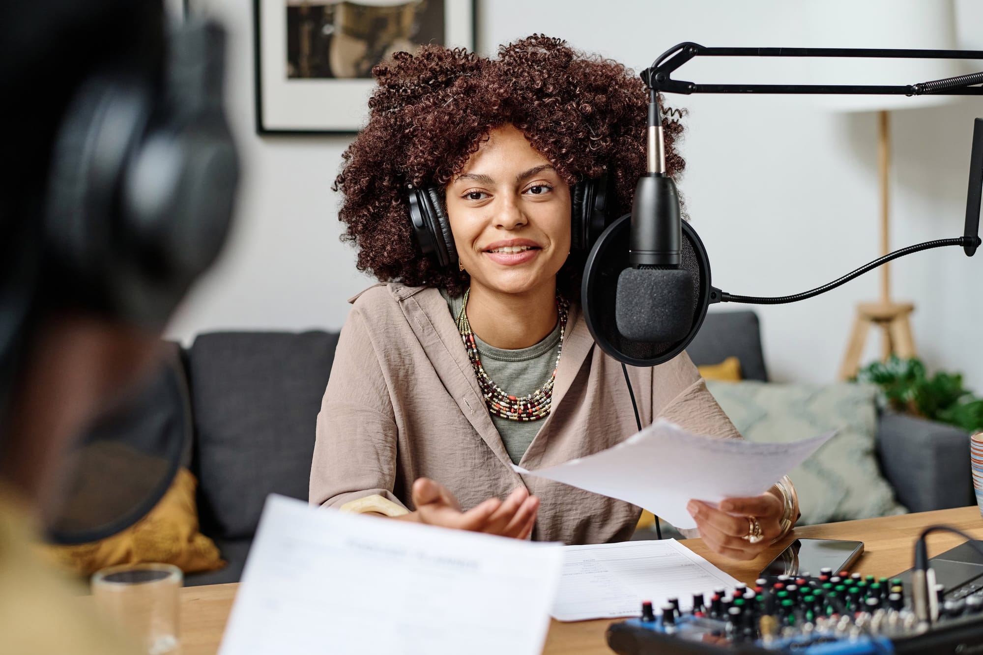 Smiling Female Podcast Presenter In Headphones Looking At Guest