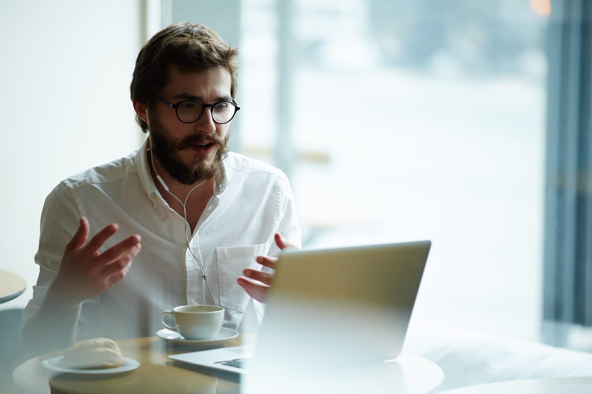 Men with glasses talking on video call with headphones and laptop.